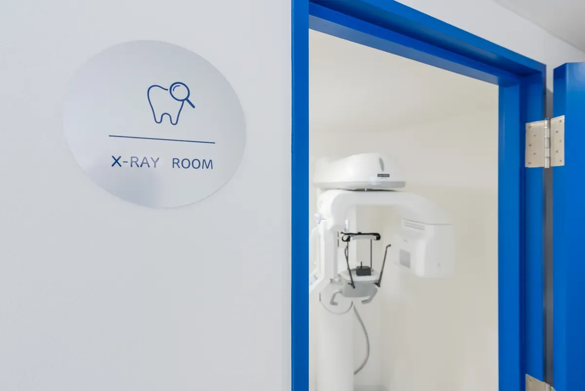 X-RAY ROOM と記した銘板と、扉の奥のレントゲン室